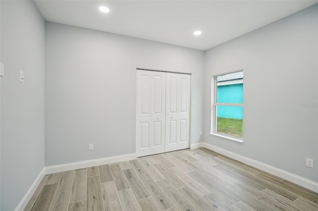 unfurnished bedroom featuring light wood finished floors, a closet, and baseboards