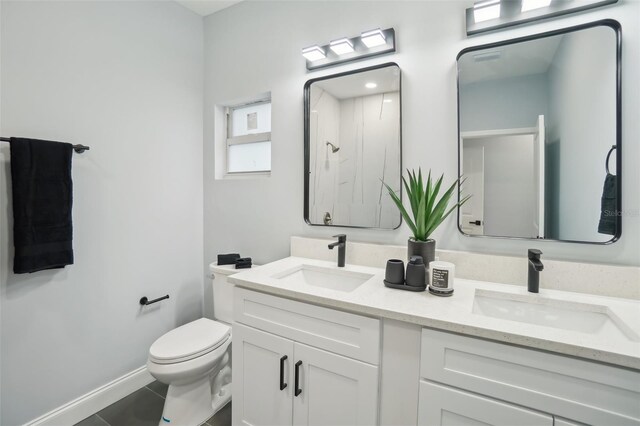 full bathroom with toilet, double vanity, baseboards, and a sink