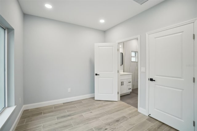 unfurnished bedroom with recessed lighting, ensuite bath, baseboards, and wood finish floors