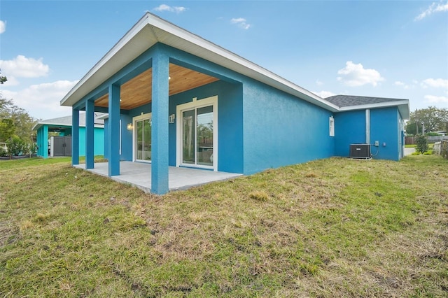 back of property featuring central air condition unit, a patio area, a lawn, and stucco siding