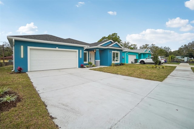 ranch-style house featuring concrete driveway, a front lawn, an attached garage, and stucco siding