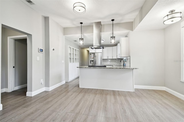 kitchen featuring white cabinets, hanging light fixtures, backsplash, stainless steel refrigerator with ice dispenser, and light hardwood / wood-style floors