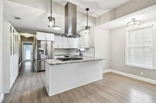 kitchen with light stone countertops, stainless steel refrigerator with ice dispenser, island range hood, and decorative light fixtures