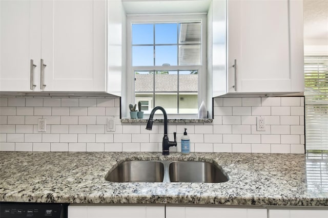 kitchen featuring a wealth of natural light, light stone counters, sink, white cabinetry, and decorative backsplash