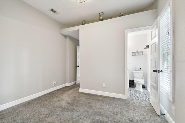 unfurnished bedroom with connected bathroom and carpet flooring