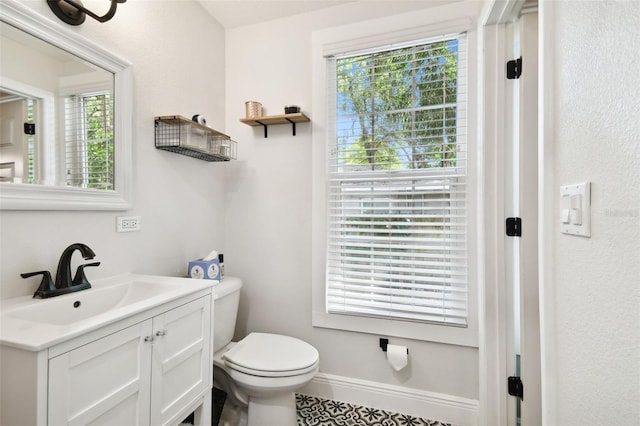 bathroom with a healthy amount of sunlight, vanity, and toilet