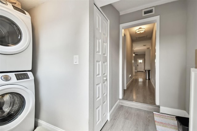 clothes washing area with stacked washer and dryer and light hardwood / wood-style flooring