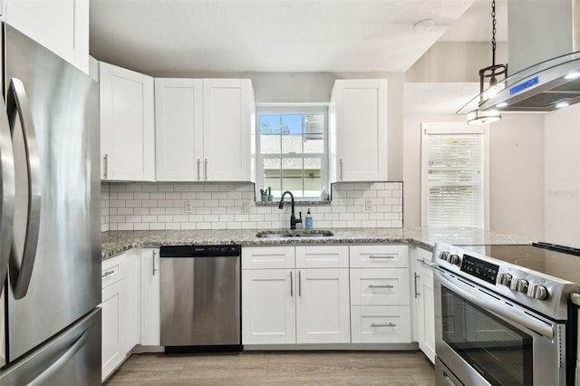 kitchen featuring light stone counters, a sink, white cabinetry, appliances with stainless steel finishes, and decorative backsplash