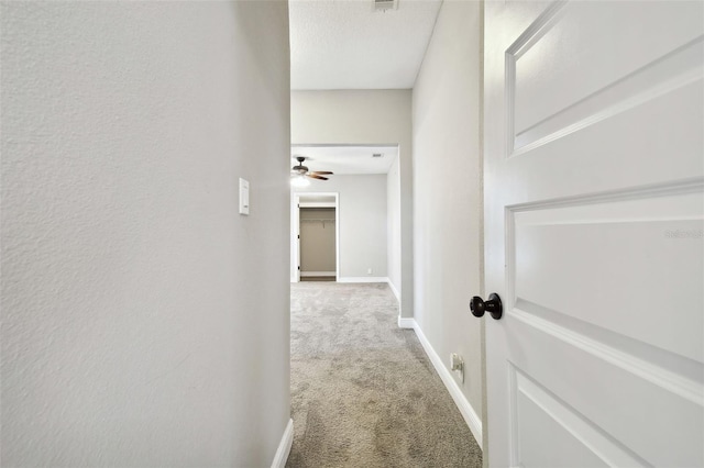 corridor with carpet flooring, visible vents, and baseboards