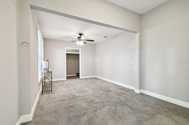 carpeted spare room with a ceiling fan, visible vents, and baseboards