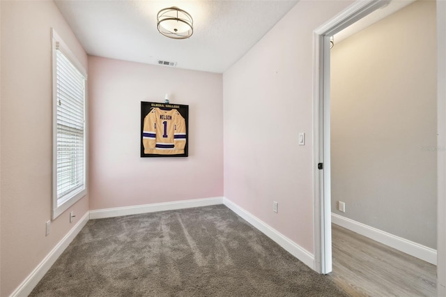 unfurnished room featuring carpet, visible vents, and baseboards