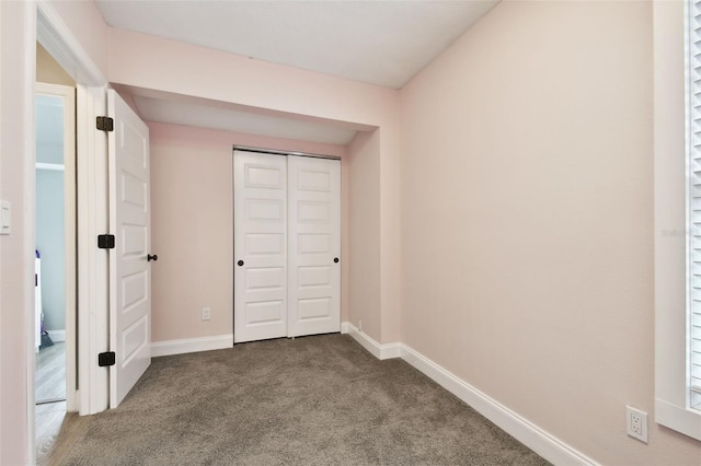 unfurnished bedroom with carpet floors, baseboards, and a closet