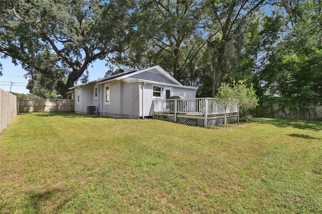 back of house with a fenced backyard, a lawn, a deck, and central AC