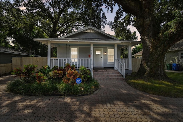 bungalow-style home with covered porch and fence