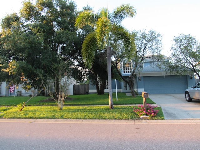 view of property hidden behind natural elements featuring a garage and a front yard