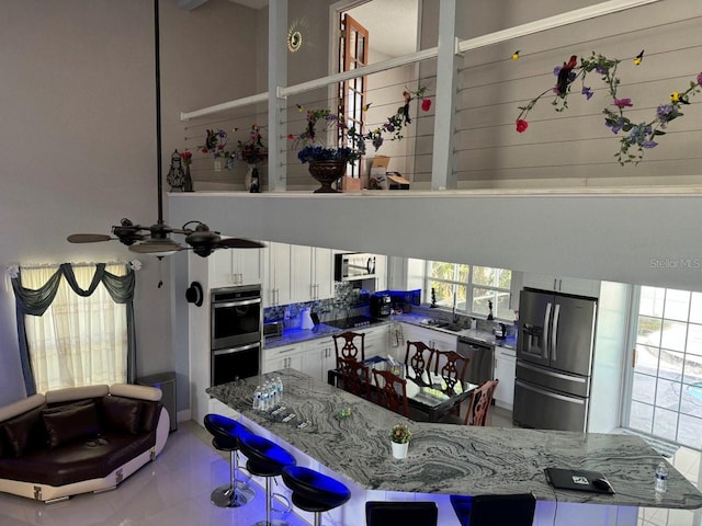 kitchen featuring dark stone counters, a healthy amount of sunlight, stainless steel appliances, and white cabinets