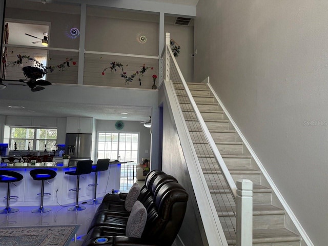 stairway with ceiling fan and indoor bar