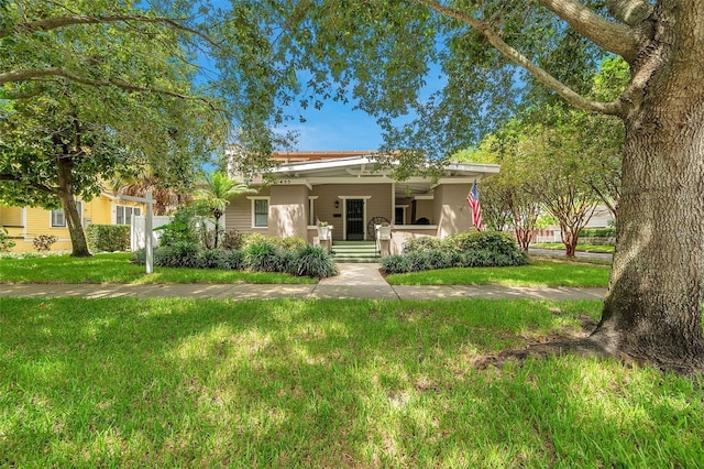 view of front of house with stucco siding, a porch, and a front yard