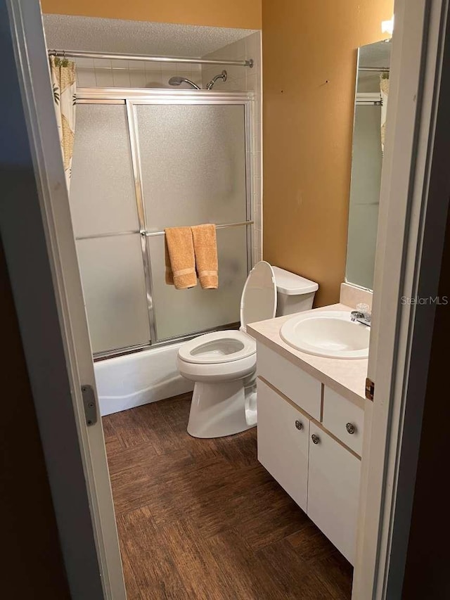 full bathroom with vanity, toilet, bath / shower combo with glass door, and parquet flooring