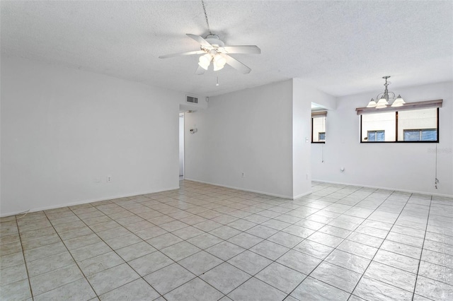 tiled spare room with a textured ceiling and ceiling fan with notable chandelier