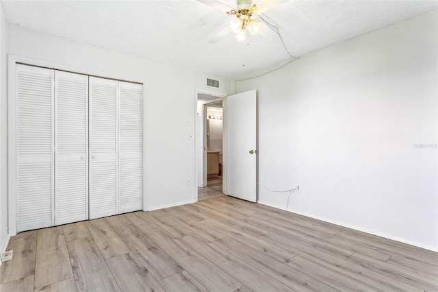 unfurnished bedroom with visible vents, wood finished floors, a closet, a textured ceiling, and a ceiling fan