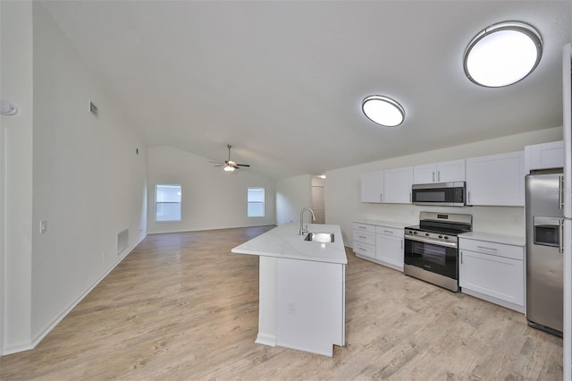 kitchen with a kitchen island with sink, white cabinets, lofted ceiling, and appliances with stainless steel finishes