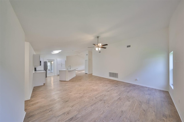 unfurnished living room with light hardwood / wood-style flooring, ceiling fan, lofted ceiling, and sink