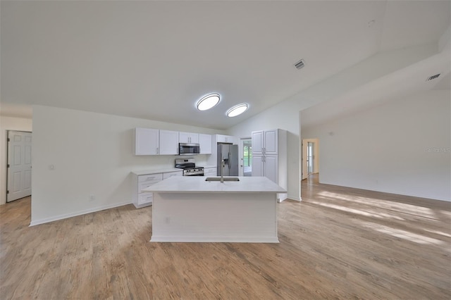 kitchen with white cabinetry, stainless steel appliances, light hardwood / wood-style floors, lofted ceiling, and a center island with sink