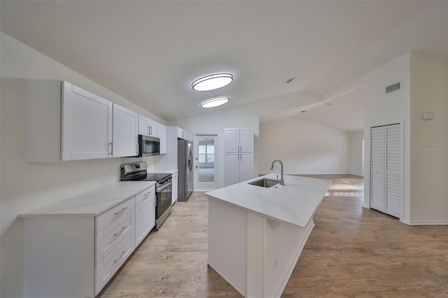 kitchen with a kitchen island with sink, white cabinets, sink, light wood-type flooring, and appliances with stainless steel finishes