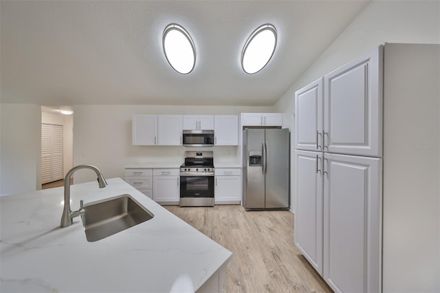 kitchen with light stone counters, sink, white cabinetry, and stainless steel appliances