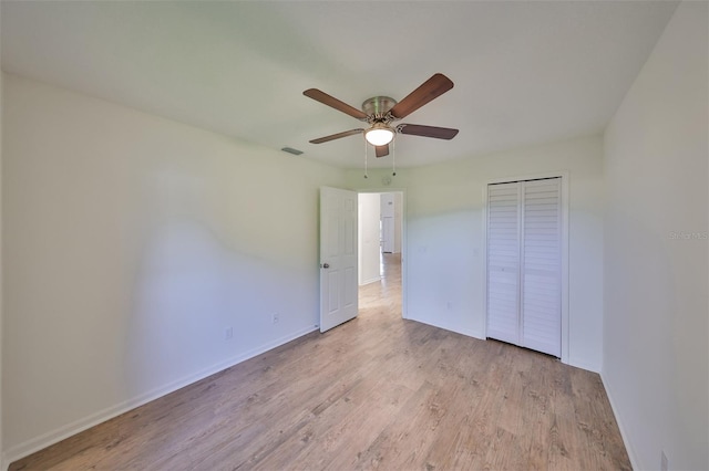 unfurnished bedroom with ceiling fan, light wood-type flooring, and a closet