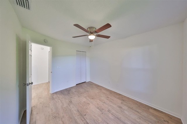 empty room with ceiling fan and light hardwood / wood-style flooring