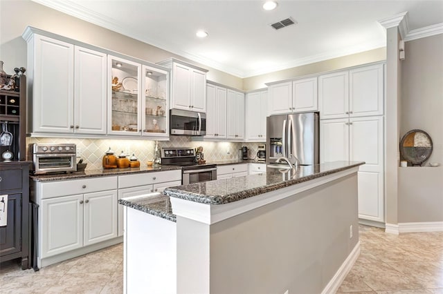 kitchen with white cabinets, appliances with stainless steel finishes, light tile patterned floors, and an island with sink