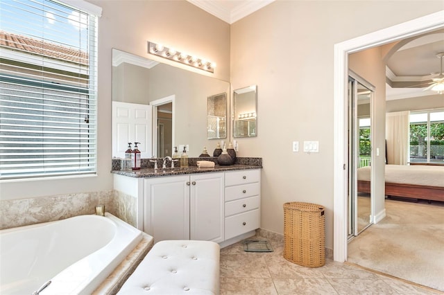 bathroom with tile patterned flooring, crown molding, ceiling fan, tiled bath, and vanity