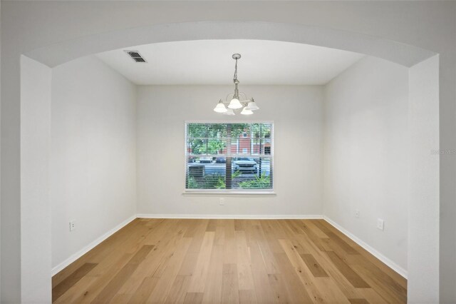 spare room with a notable chandelier and hardwood / wood-style floors