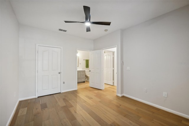 unfurnished bedroom featuring ceiling fan, ensuite bathroom, and light hardwood / wood-style flooring