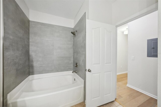 bathroom with tub / shower combination, electric panel, and hardwood / wood-style flooring