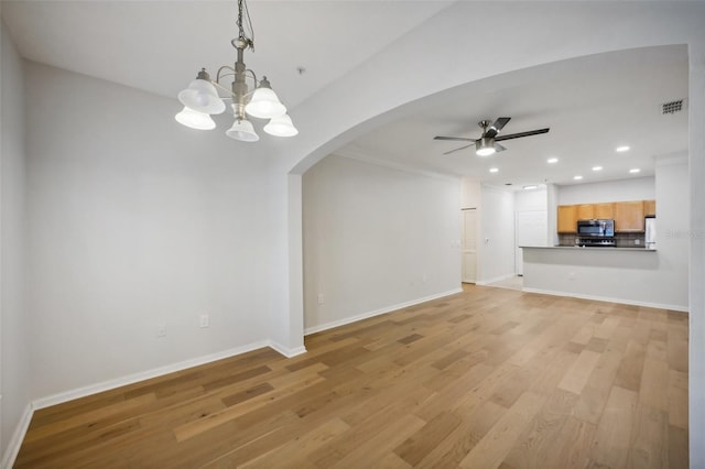 unfurnished living room with visible vents, arched walkways, light wood-style floors, and ceiling fan with notable chandelier