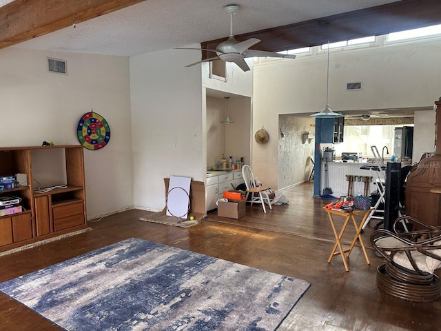 living room with dark wood-type flooring, ceiling fan, and beam ceiling