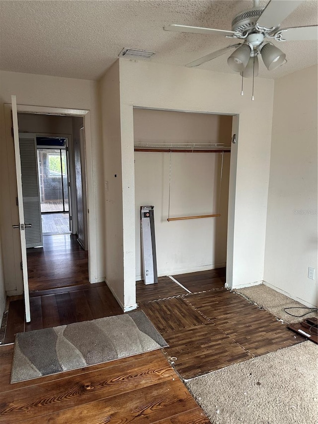 interior space featuring a closet, dark hardwood / wood-style floors, a textured ceiling, and ceiling fan