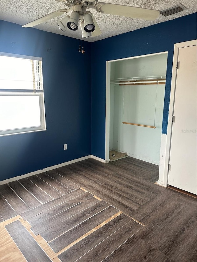 unfurnished bedroom featuring dark wood-type flooring, ceiling fan, a closet, and a textured ceiling