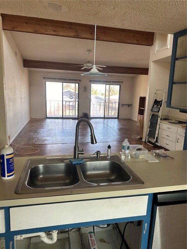 kitchen with beamed ceiling, sink, white cabinetry, and ceiling fan