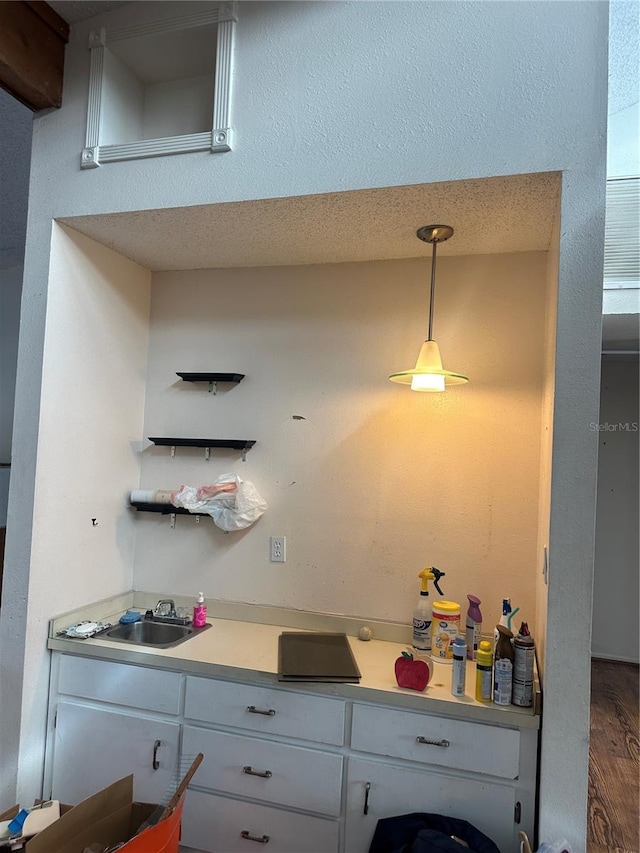 kitchen with white cabinets, sink, hardwood / wood-style floors, and hanging light fixtures