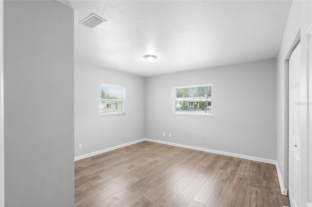 empty room with a textured ceiling and light hardwood / wood-style floors