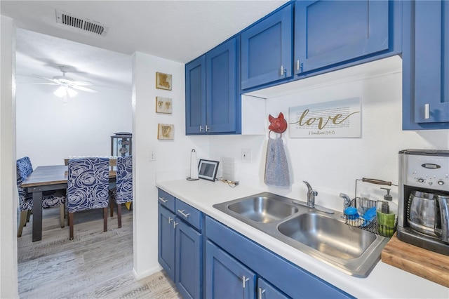 kitchen featuring light wood-type flooring, ceiling fan, blue cabinets, and sink