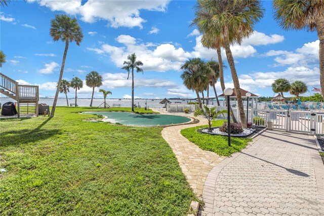 view of property's community with a water view and a lawn