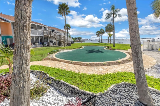 surrounding community with a water view and a lawn