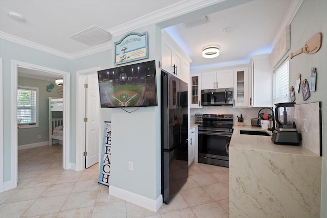 kitchen with appliances with stainless steel finishes, decorative backsplash, white cabinets, light tile patterned floors, and ornamental molding