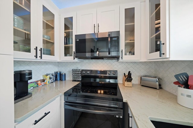 kitchen with light stone counters, white cabinets, appliances with stainless steel finishes, and tasteful backsplash