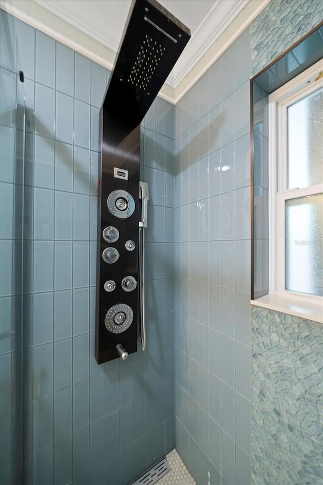 bathroom with crown molding and a tile shower